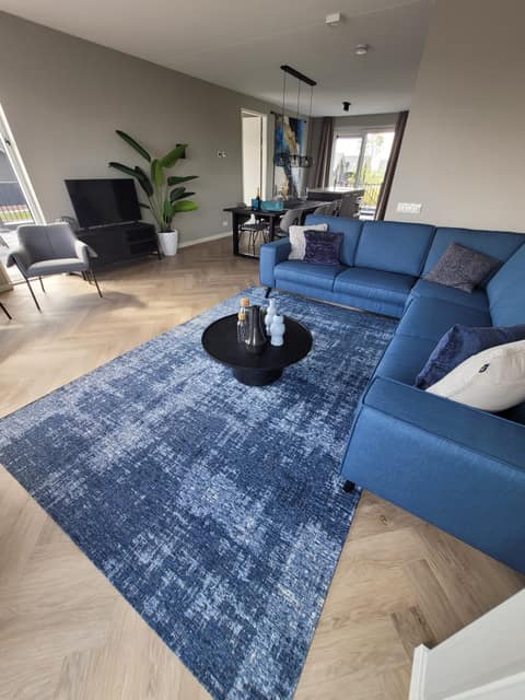 Sitzecke mit Ecksofa und blauem Teppich
